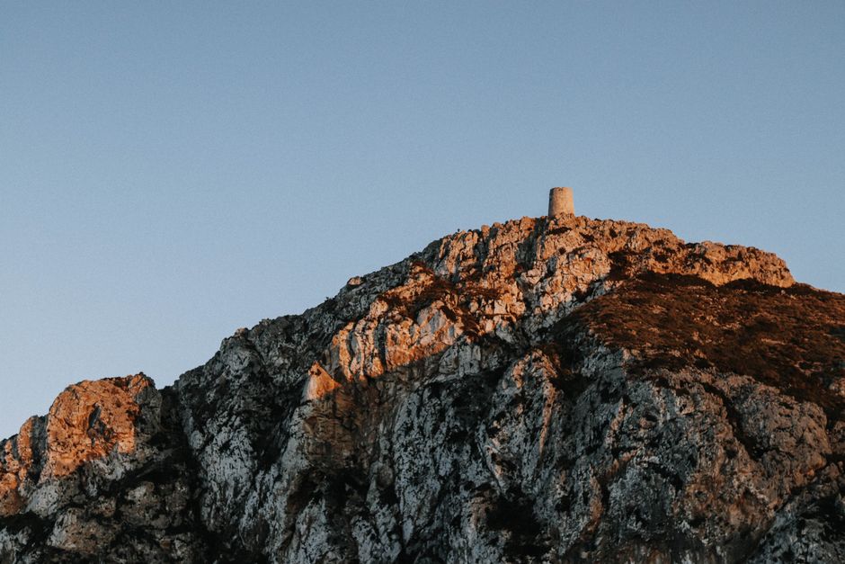 Une vue saisissante d'une montagne rocheuse avec une tour isolée au crépuscule, capturant la beauté sereine de la nature.