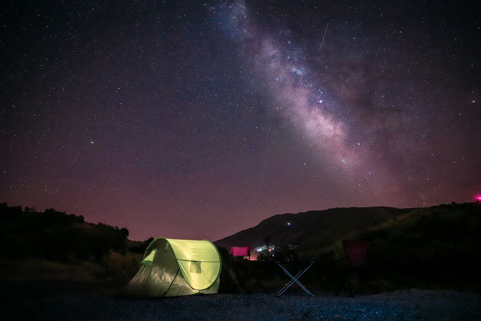 Une scène de camping tranquille sous un ciel vibrant de Voie Lactée dans un paysage montagneux.