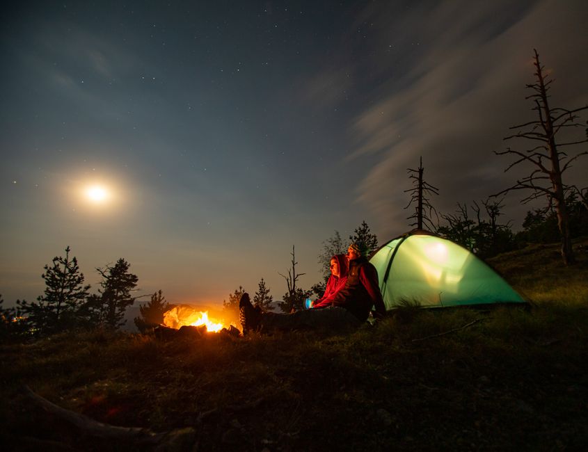 Couple profitant d'un feu de camp sous un ciel étoilé dans le paysage serein de la Bosnie.