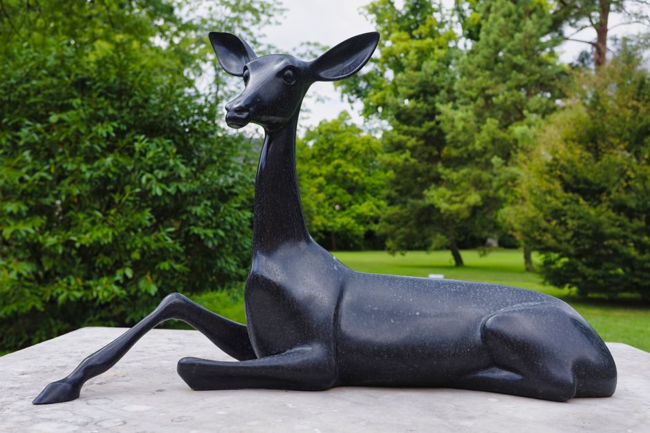 Une statue de cerf noir sereine à Fontainebleau, entourée de verdure dans un cadre de parc paisible.