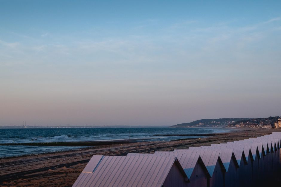 Scène de plage paisible avec des cabanes colorées à Villers-sur-Mer, Normandie. Parfait pour des vacances sereines.